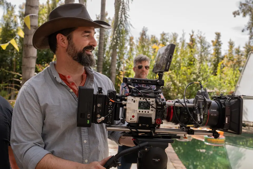 Camera operator standing beside a fully built cinema camera on the Bar-S Guy set