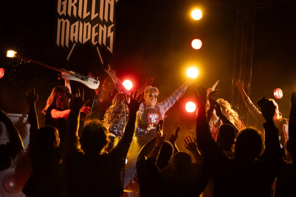 Bar-S Guy cast celebrating with a concert crowd under stage lights