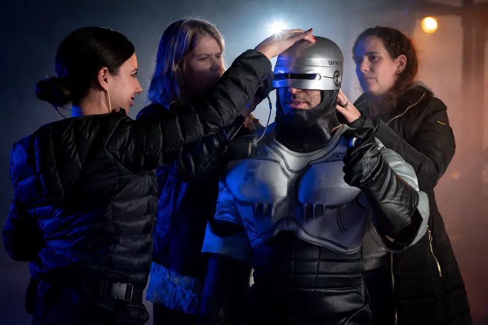 Character team fitting a futuristic helmet before a take