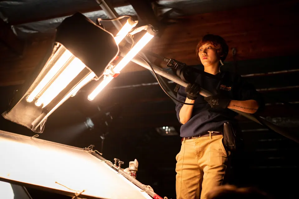 Grip crew member adjusting fluorescent stage lights