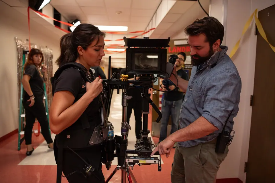 Camera team balancing a Steadicam rig in a dressed school hallway