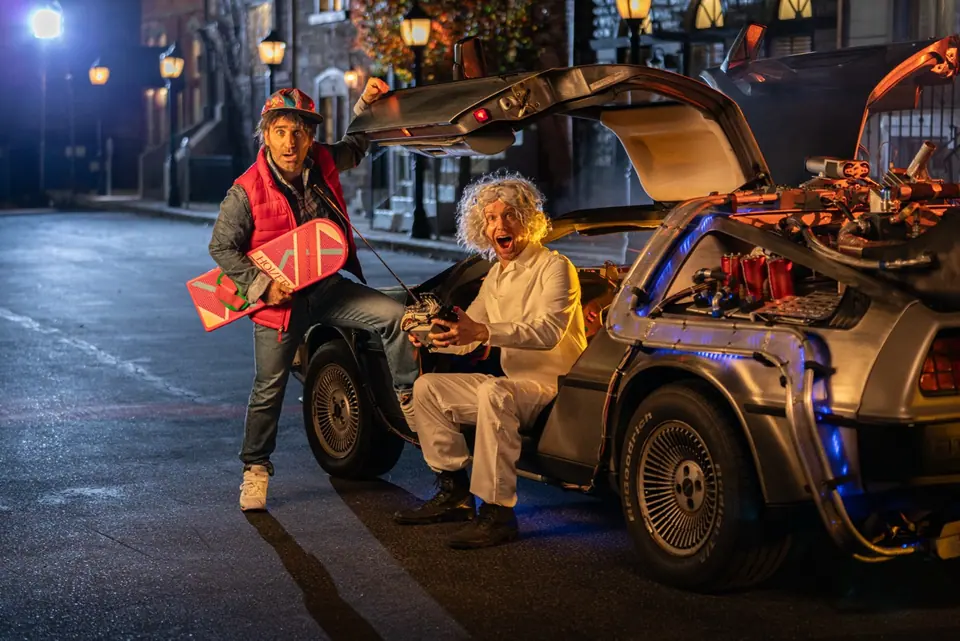 Back to the 80s performers beside a practical DeLorean on a city set
